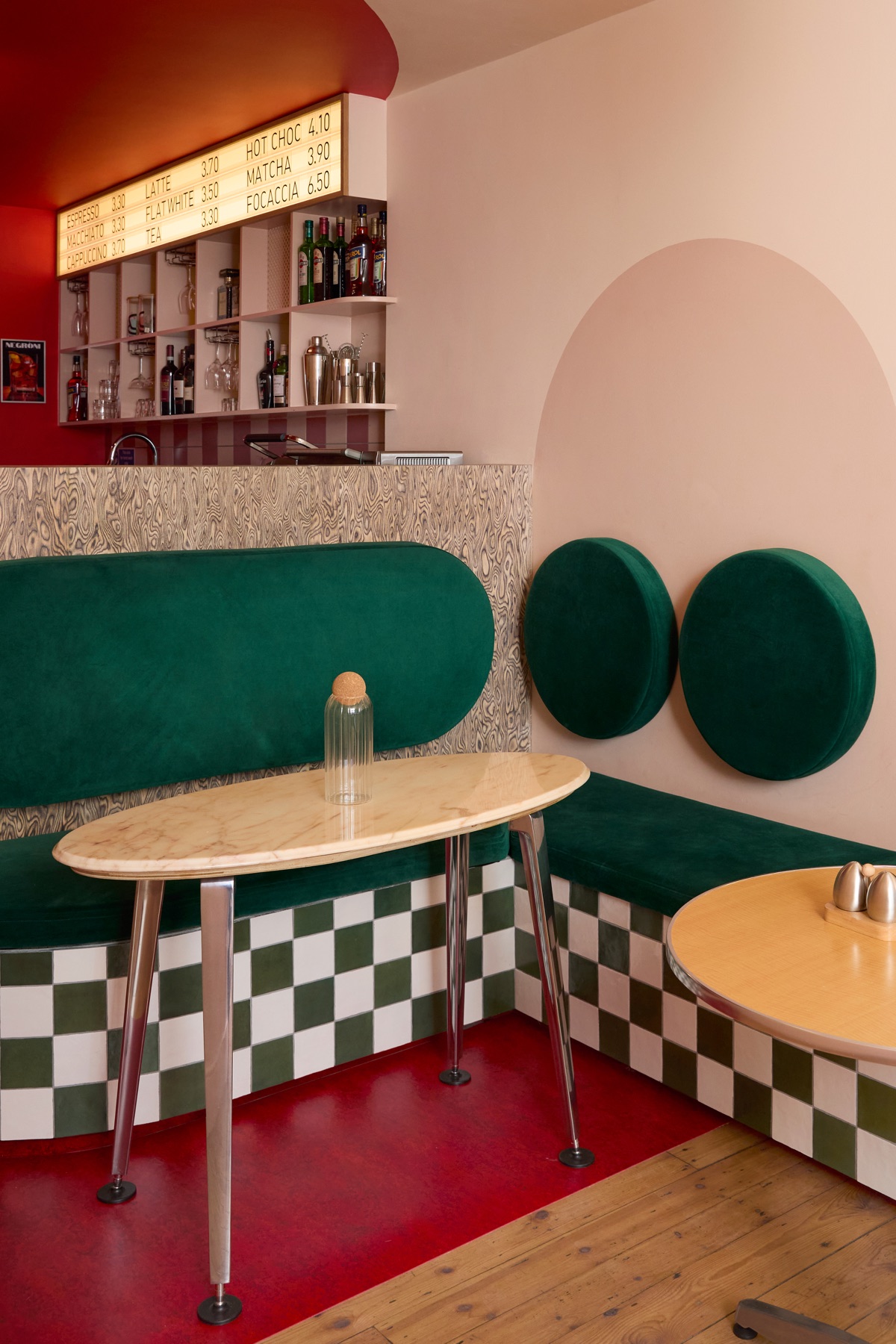 Green velvet banquette with oval wall panels and marble table