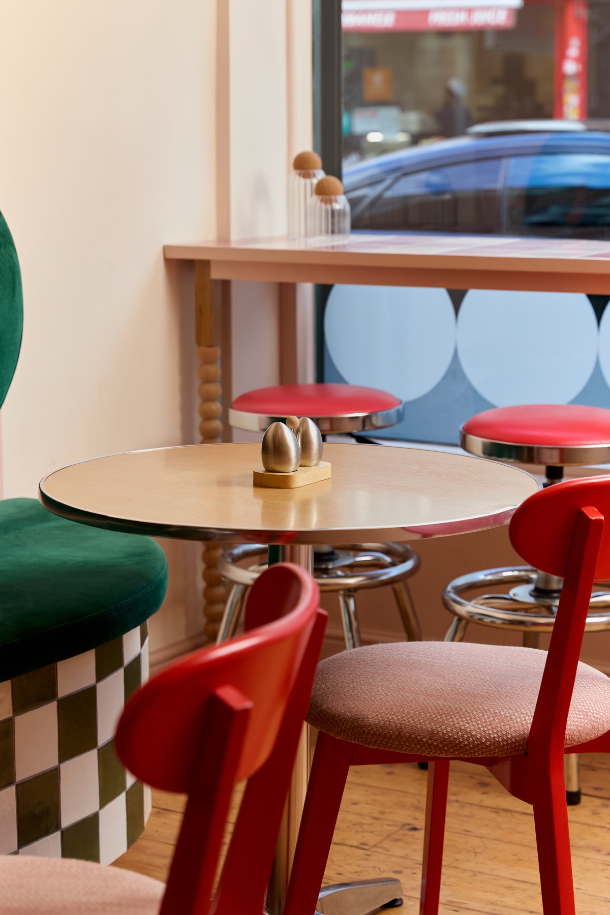 Red chairs and bar stools around a cafe table by the window